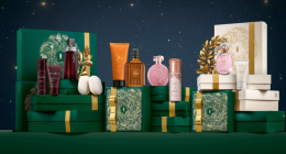 Embalagens de Natal do Boticário em tons de verde e dourado, com kits sofisticados dispostos em cenário iluminado, transmitindo elegância e clima festivo